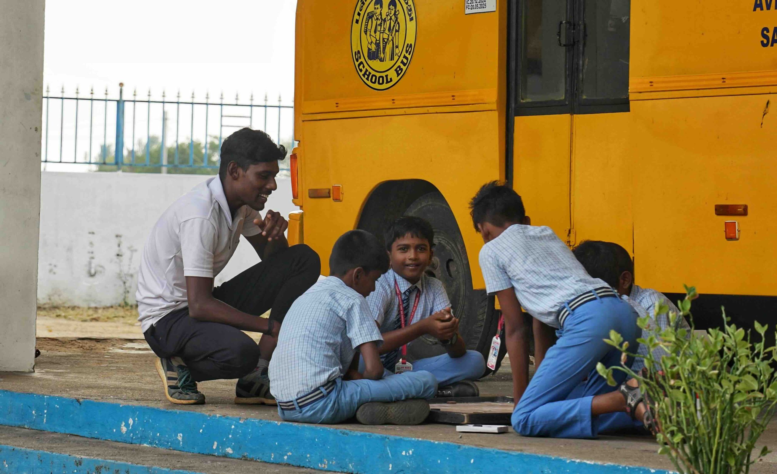 Students playing Carrom with their physical education teacher during Playtime